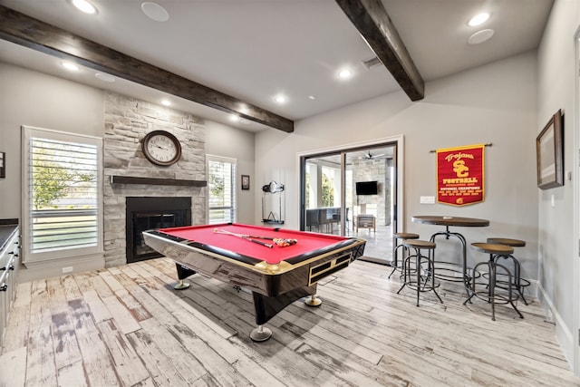 game room featuring beamed ceiling, plenty of natural light, light hardwood / wood-style floors, and a fireplace