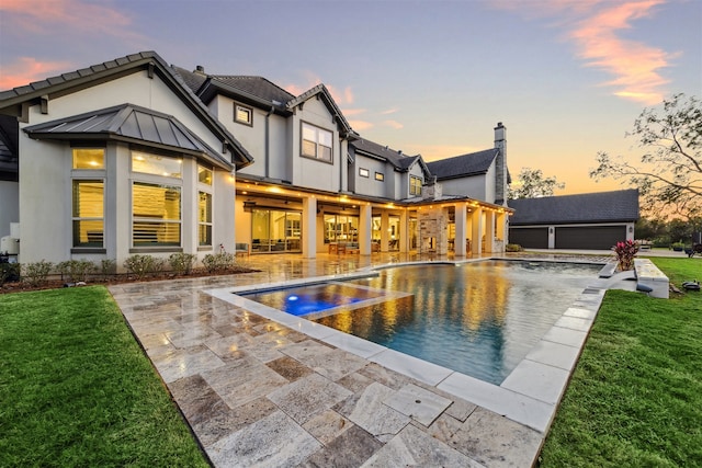 back house at dusk featuring an outdoor structure, a patio area, and a yard