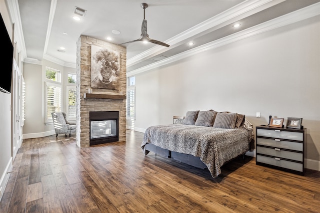 bedroom featuring crown molding, ceiling fan, dark wood-type flooring, and a stone fireplace