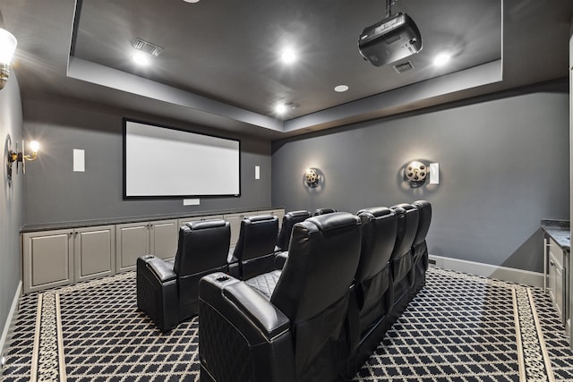 cinema featuring a raised ceiling and dark carpet