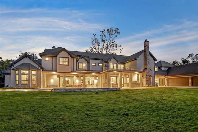 back house at dusk featuring a yard