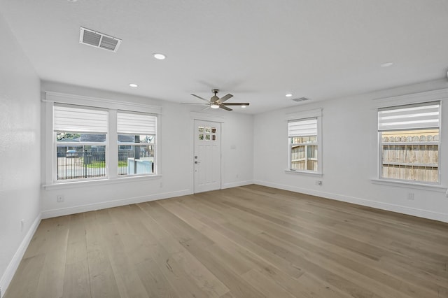 unfurnished living room featuring plenty of natural light, ceiling fan, and light hardwood / wood-style flooring