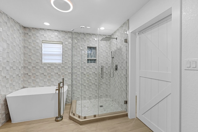 bathroom featuring wood-type flooring and shower with separate bathtub