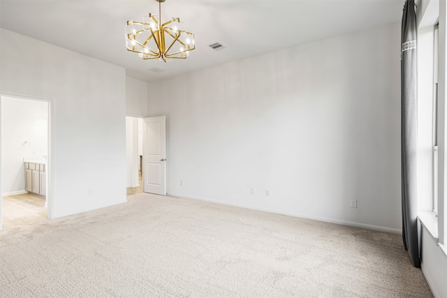 carpeted spare room with a notable chandelier