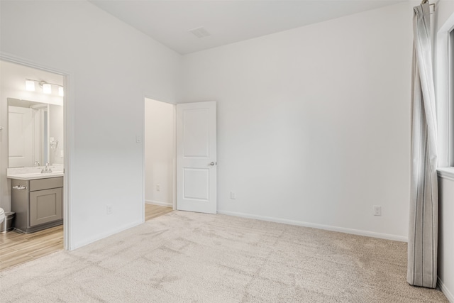 unfurnished bedroom featuring connected bathroom and light carpet