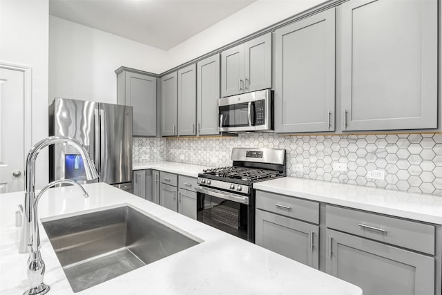 kitchen with gray cabinets, decorative backsplash, sink, and stainless steel appliances