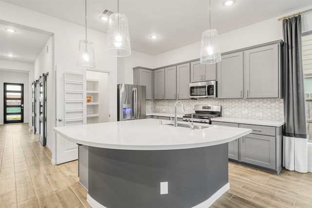 kitchen featuring a barn door, decorative backsplash, sink, and appliances with stainless steel finishes