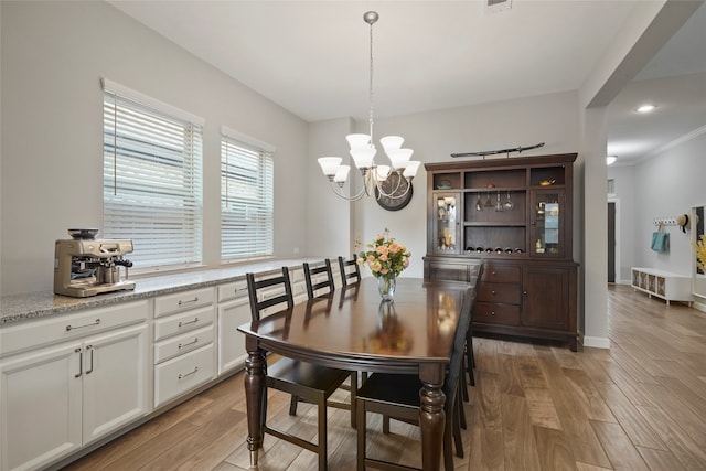 dining area with crown molding, light hardwood / wood-style floors, and a notable chandelier