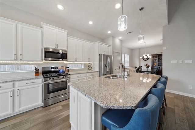 kitchen featuring a kitchen island with sink, sink, stainless steel appliances, and light hardwood / wood-style floors