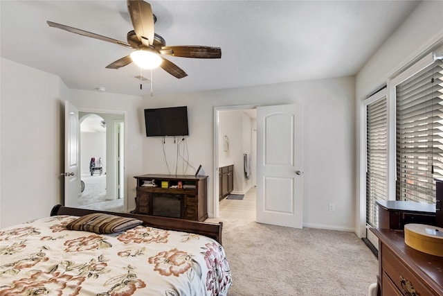 bedroom featuring ensuite bath, ceiling fan, and light carpet