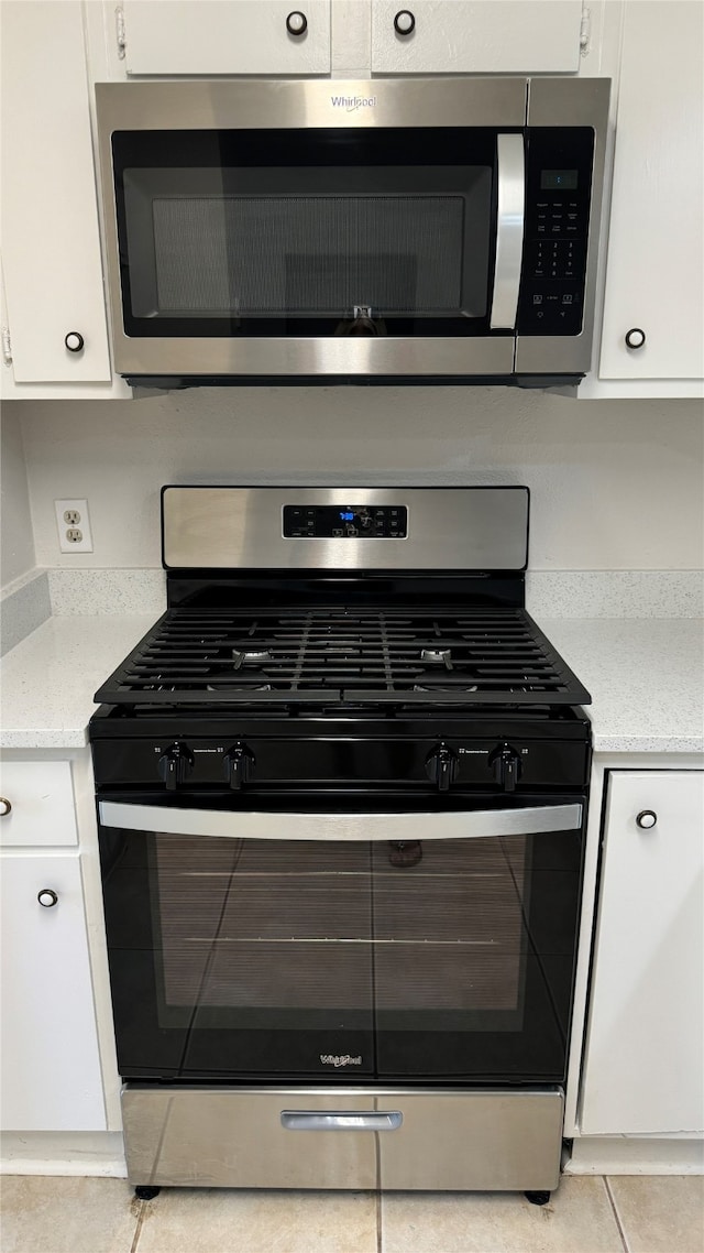 kitchen featuring stainless steel appliances, white cabinetry, and light tile patterned flooring