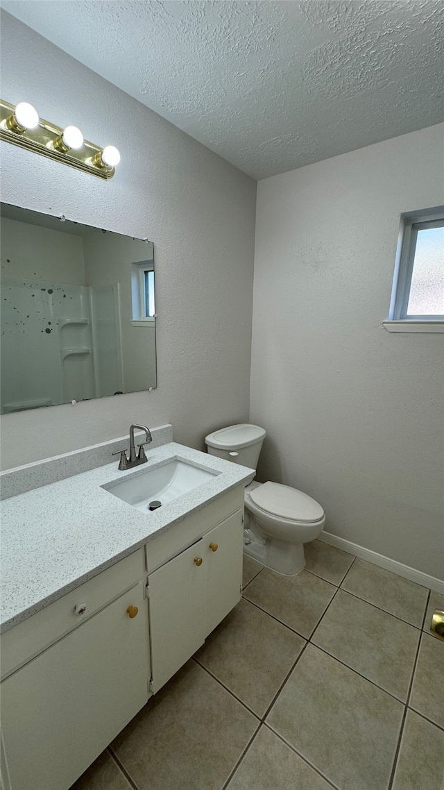 bathroom with tile patterned flooring, vanity, a textured ceiling, and toilet