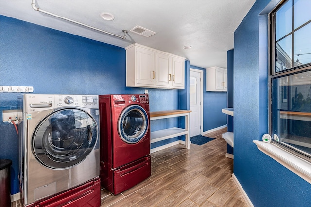 laundry room with independent washer and dryer, cabinets, and wood-type flooring