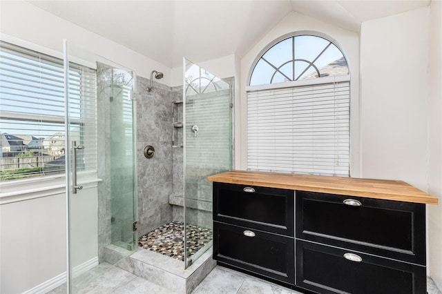 bathroom featuring a shower with shower door and vaulted ceiling