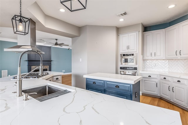 kitchen featuring white cabinetry, light stone countertops, blue cabinetry, and light hardwood / wood-style flooring