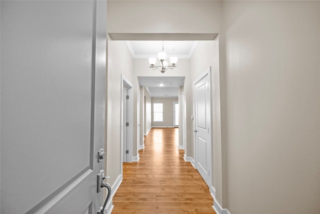 corridor featuring light hardwood / wood-style flooring, a chandelier, and ornamental molding