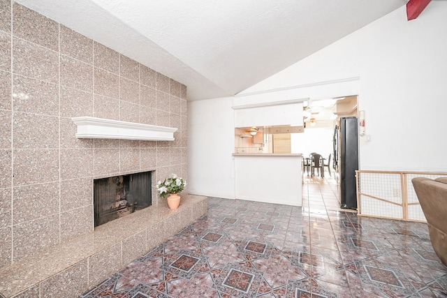 unfurnished living room with a fireplace, vaulted ceiling, and tile walls