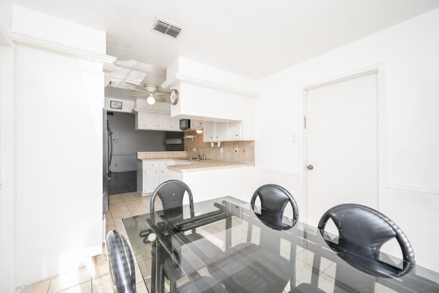 kitchen with kitchen peninsula, tasteful backsplash, white cabinetry, and light tile patterned flooring