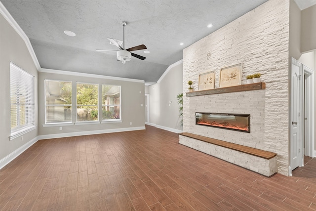 unfurnished living room featuring a stone fireplace, a wealth of natural light, hardwood / wood-style floors, and lofted ceiling