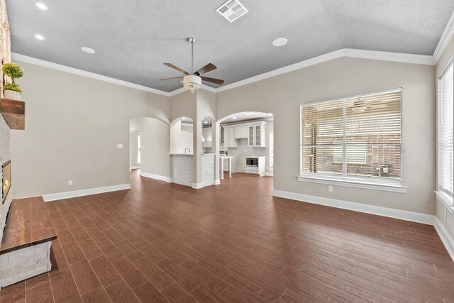 unfurnished living room with ceiling fan, dark hardwood / wood-style flooring, a textured ceiling, vaulted ceiling, and ornamental molding