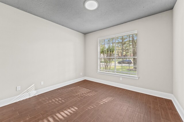 unfurnished room featuring a textured ceiling and dark hardwood / wood-style floors