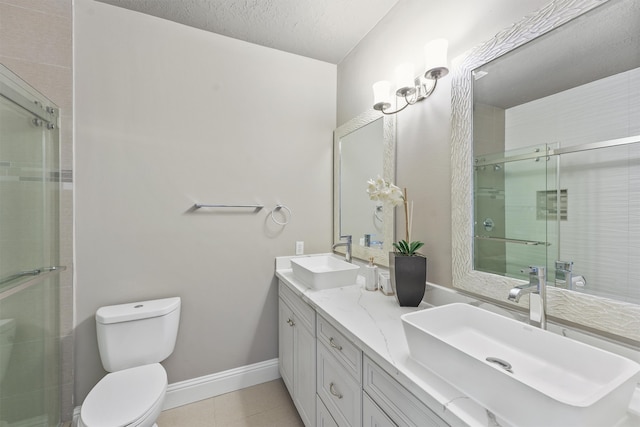 bathroom with tile patterned floors, a shower with door, vanity, toilet, and a textured ceiling