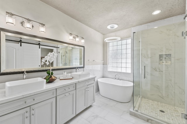 bathroom with tile walls, vanity, a textured ceiling, and shower with separate bathtub