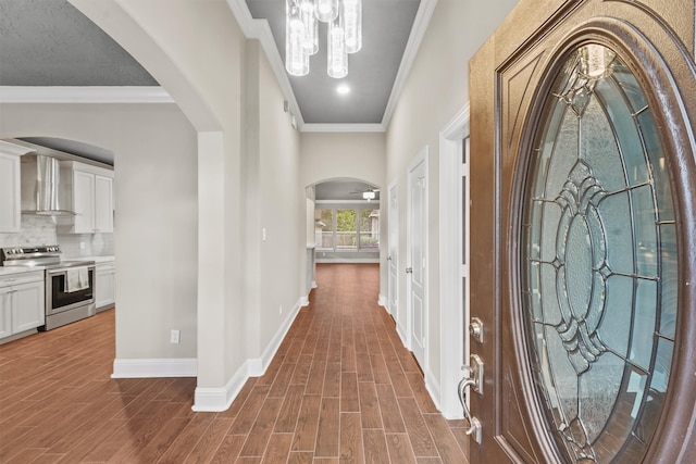 hallway with hardwood / wood-style floors, ornamental molding, and an inviting chandelier