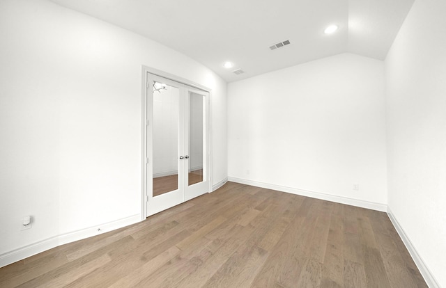 unfurnished room featuring french doors, light wood-type flooring, and lofted ceiling