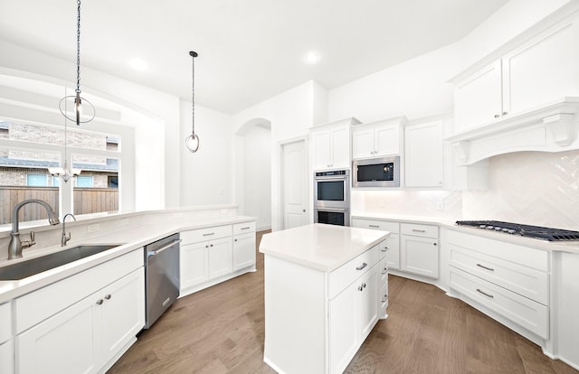 kitchen featuring dark hardwood / wood-style flooring, stainless steel appliances, sink, decorative light fixtures, and white cabinets