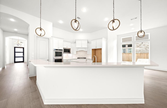 kitchen featuring a large island with sink, hardwood / wood-style floors, white cabinets, and appliances with stainless steel finishes