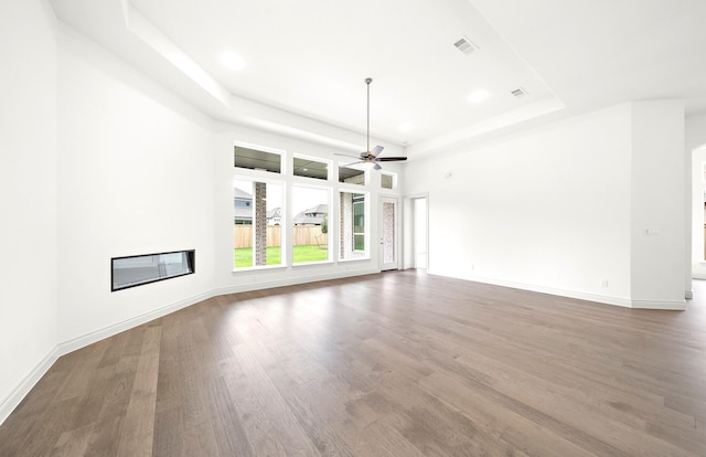 unfurnished living room with hardwood / wood-style flooring, ceiling fan, and a tray ceiling