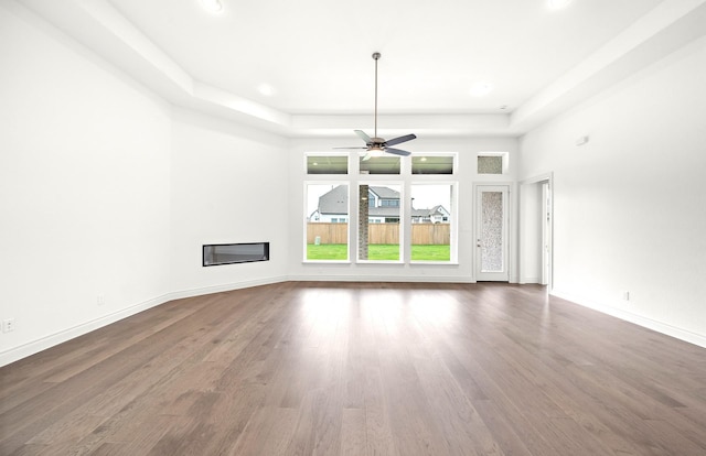 unfurnished living room featuring wood-type flooring and a raised ceiling