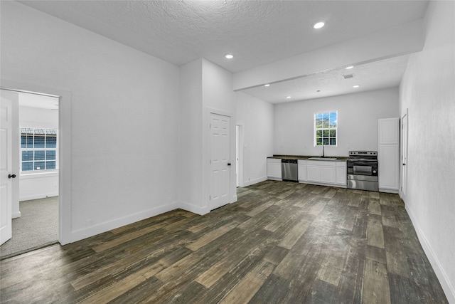 unfurnished living room with a textured ceiling and dark hardwood / wood-style floors