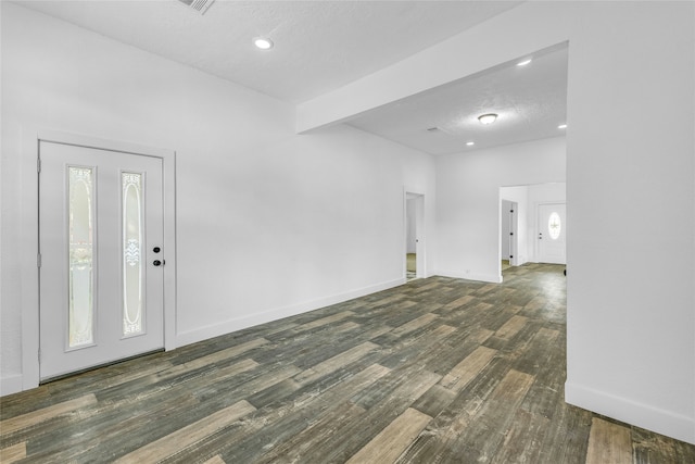 entryway with beamed ceiling, dark wood-type flooring, and a textured ceiling