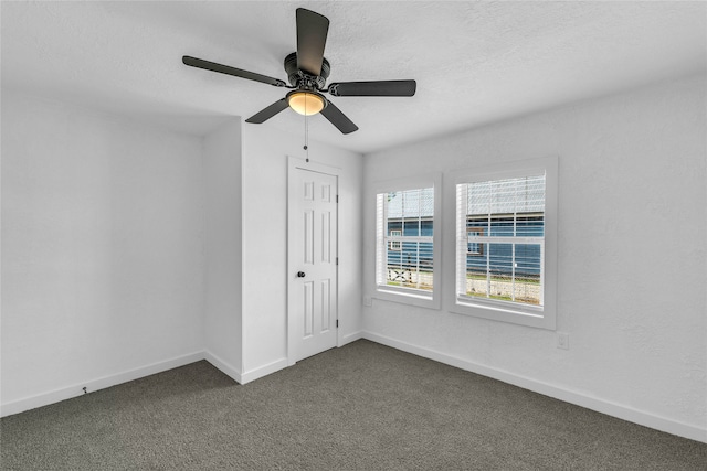 unfurnished room with ceiling fan, a textured ceiling, and dark colored carpet