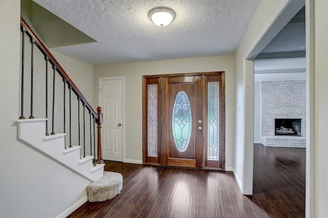 entrance foyer with a textured ceiling, dark hardwood / wood-style floors, and a brick fireplace