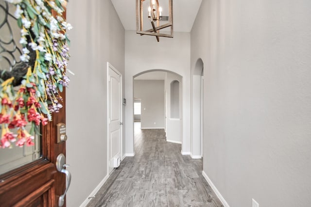 corridor featuring wood-type flooring and a high ceiling