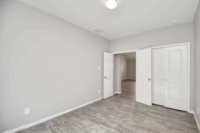 unfurnished bedroom featuring light hardwood / wood-style flooring and a closet