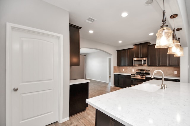 kitchen featuring sink, pendant lighting, dark brown cabinets, light wood-type flooring, and stainless steel appliances