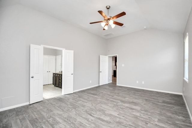 unfurnished bedroom with light hardwood / wood-style flooring, high vaulted ceiling, ceiling fan, and connected bathroom