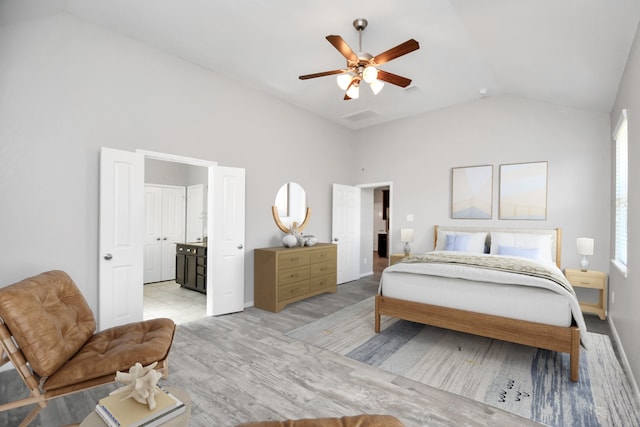 bedroom featuring connected bathroom, ceiling fan, light hardwood / wood-style floors, and vaulted ceiling