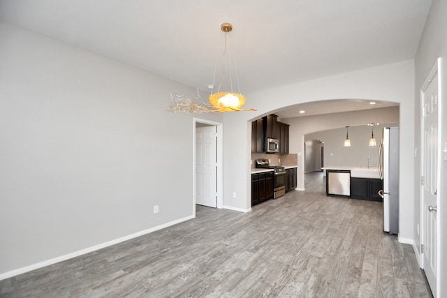 kitchen with light hardwood / wood-style floors, hanging light fixtures, stainless steel appliances, and dark brown cabinetry