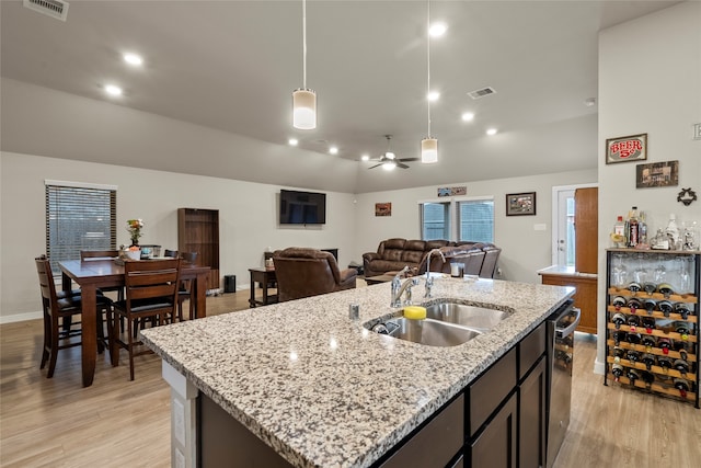 kitchen with sink, an island with sink, pendant lighting, and light hardwood / wood-style flooring