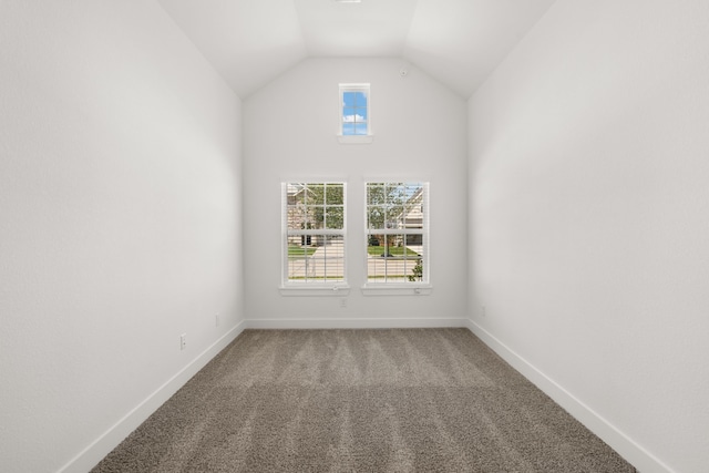 carpeted spare room featuring vaulted ceiling and plenty of natural light