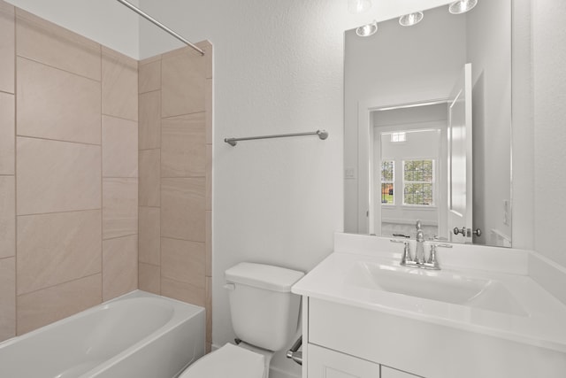 full bathroom featuring tiled shower / bath, vanity, and toilet