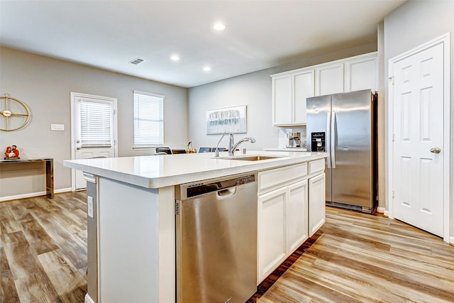 kitchen with stainless steel appliances, sink, light hardwood / wood-style flooring, white cabinets, and an island with sink