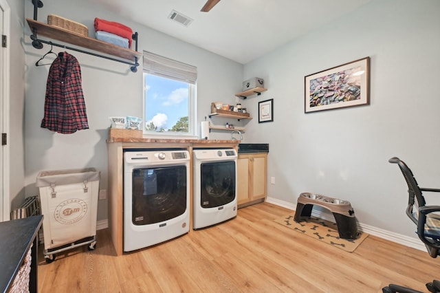 clothes washing area featuring washer and clothes dryer, cabinets, and light wood-type flooring