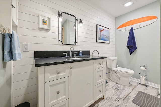 bathroom featuring hardwood / wood-style flooring, vanity, toilet, and wooden walls