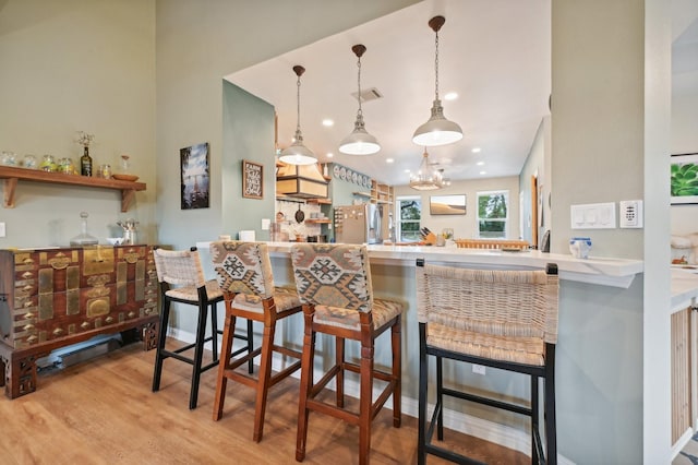 kitchen with kitchen peninsula, stainless steel refrigerator with ice dispenser, and a breakfast bar area